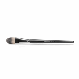 Großer, breiter Concealer-Pinsel (tierhaarfrei) liegt auf weißer Fläche.