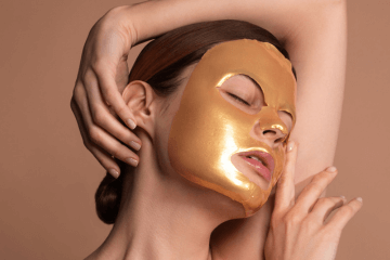 Frau trägt eine goldene Gesichtsmaske zu Beauty-Zwecken.
